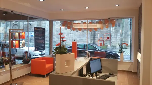 Modernes Hörakustik-Fachgeschäft mit Empfangstresen, Wartebereich und Dekoration.