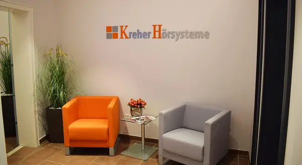 Moderner Wartebereich bei Kreher Hörsysteme mit farbigen Sesseln und Pflanzen.