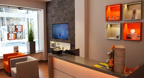 Modern eingerichteter Hörakustik-Laden mit Empfangstheke, Wartebereich und Produktpräsentation.